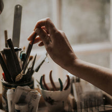 Person holding a jewellery file over a container of jewellery supplies with a blurred background