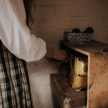 Person wearing a white shirt and plaid dress using jewellers polishing motor 