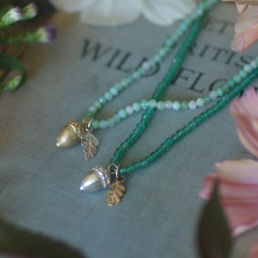 Two green beaded necklaces with leaf pendants on a book titled 'Wild Flowers'.