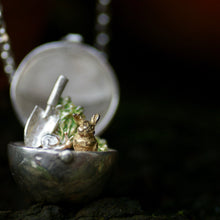 Small silver locket with a rabbit sitting in an allotment in a natural environment 