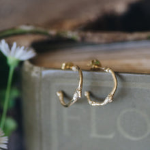 Gold hoop earrings on a book with flowers in the background